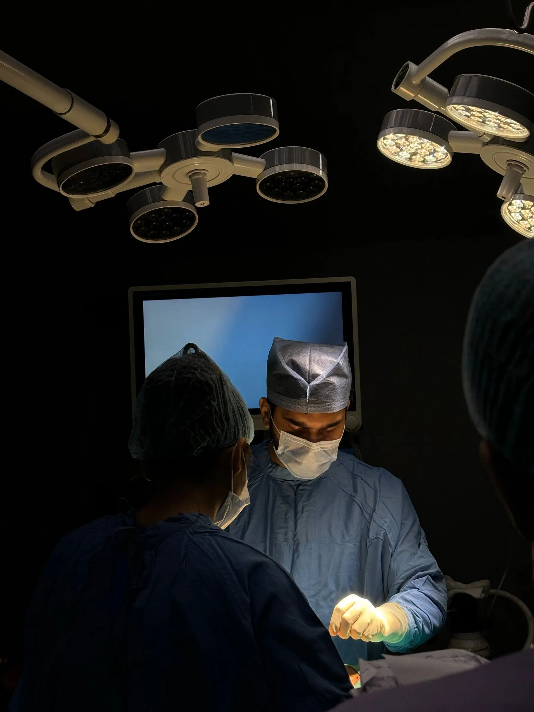 Ästhetisches Chirurgenteam bei der Arbeit unter Operationsleuchten in einem modernen Operationssaal